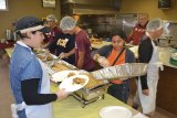 Volunteers at the 2014 dinner dish up turkey and stuffing.